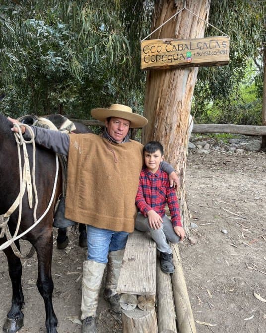 Miguel, de Eco Cabalgatas Codegua, junto a su caballo y al letrero de entrada